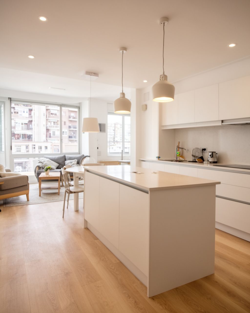 Cocina reformada con muebles blancos y suelo de madera